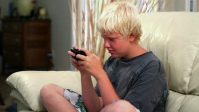 Kid playing video games ignores house cleaner