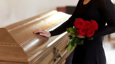 woman at casket with roses