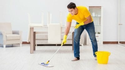 Learn to Clean man strains back stooping to mop floor