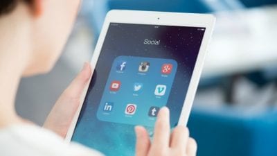 Social Media Presence Man holds tablet with social media icons