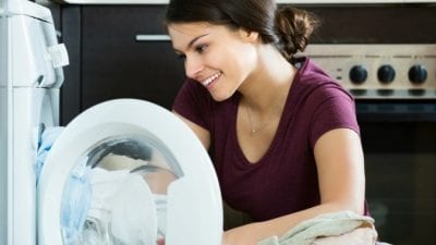 Guest Room Clean-Up young woman taking bedsheets and towels out of the dryer