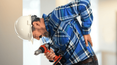 How Workers Compensation Works handyman with drill holding his back in pain