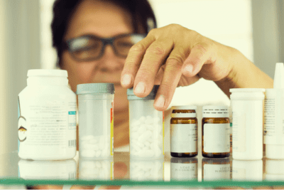 Medicine Cabinet, Woman Looking at Bottle of Pills in Medicine Cabinet