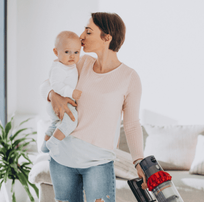 Cleaning While Pregnant, Woman Holds Baby While Vacuuming