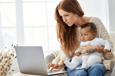 Notice to Raise Rates, Woman Holds Baby While Looks at Computer